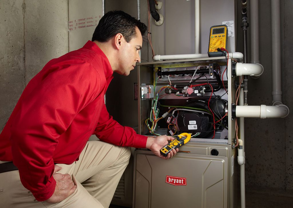 Heating and air conditioning technician servicing an indoor furnace in Golden, CO