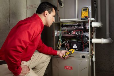 Heating and air conditioning technician servicing an indoor furnace in Golden, CO
